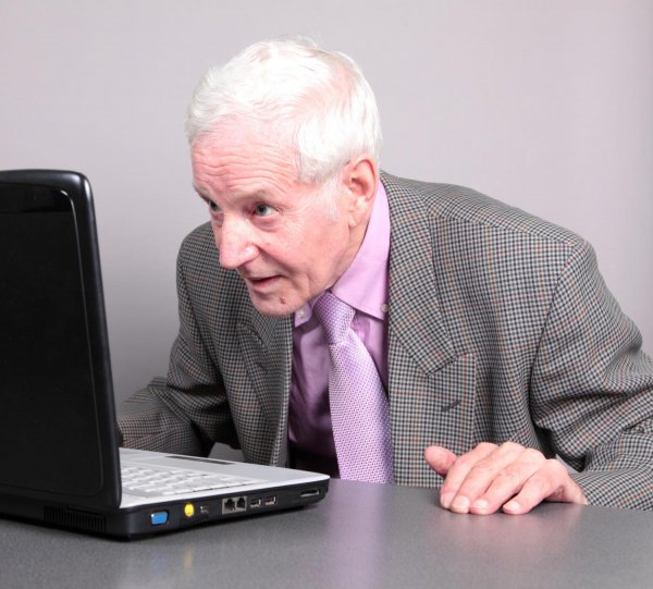 Zdziwiony starszy człowiek przed komputerem